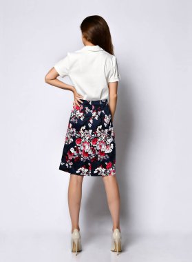 İnzivaya çekilmiş genç bir kadının arkasından manzara, resmi açık bir bluz, çiçekli açık renkli bir etek ve yüksek topuklu ayakkabılar..