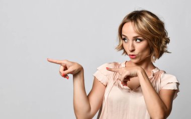 Kıvırcık saç modeli ile güzel sarışın kız yan işaret . Ürününüzü sunmak. Etkileyici yüz ifadeleri duygular