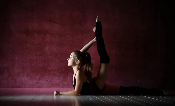 Adolescente flessibile, bella piccola ginnasta che fa esercizi ginnici per l'esercizio in classe di fitness, sfondo scuro . — Foto Stock