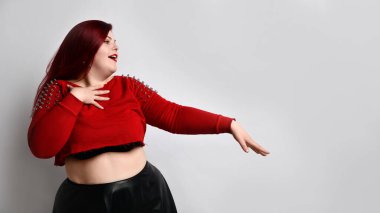 Kırmızı kazıklı, siyah sütyenli, deri etekli, obez kadın. Birinin elini öpmesine izin vermek gibi, beyazlar içinde yalnız poz vermek.