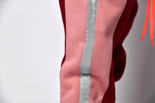 Foto recortada de uma menina em calças de camisola quentes rosa. Ela colocou uma mão em seu bolso, posando contra um fundo de estúdio branco. O conceito de infância, moda, publicidade e esportes . — Fotografia de Stock
