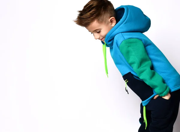 Pequeno filho de fato de treino colorido. Sorrindo, coloque as mãos nos bolsos, posando de lado isolado no fundo do estúdio branco — Fotografia de Stock