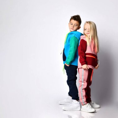 Siyah saçlı erkek ve şık jimnastik elbiseli sarışın kız sırt sırta dururlar. Açık gri üzerine izole edilmiş portre, boşluğu kopyala