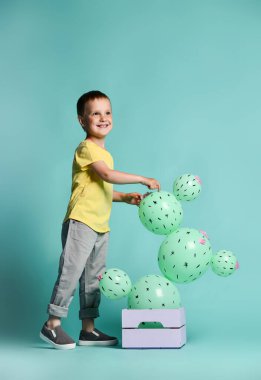Neşeli küçük çocuk ve kutuda yeşil kaktüs şeklinde balonlar. Çekiliş