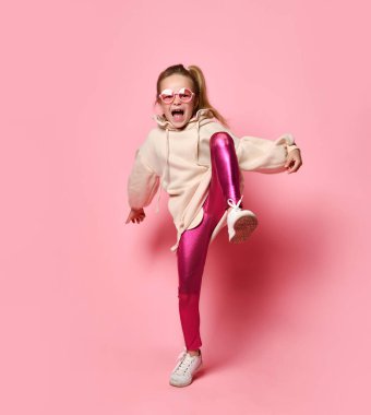 Sarışın holigan ayağını yere vuruyor, poz veriyor, çığlıklara öfkeleniyor, pembe stüdyo arka planında..