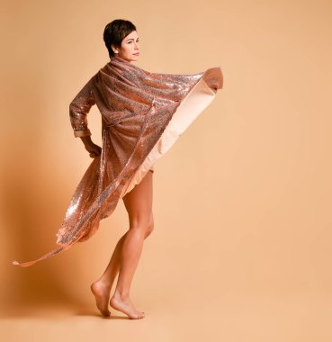 Gülümseyen esmer kadın, kısa saçlı, seksi pembe, parlak gece kostümü giymiş, mini elbisesi çıplak ayaklı.