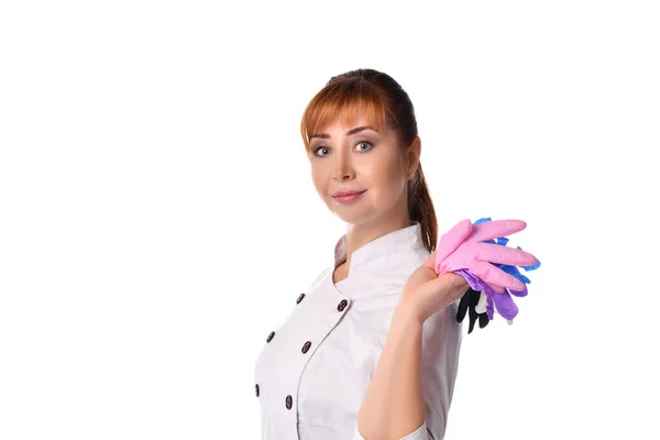 Femme, infirmière ou médecin, en costume médical pose isolé sur blanc. Elle sourit et tient des gants jetables colorés — Photo