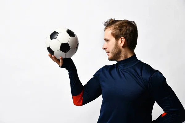 Hombre rubio, jugador de fútbol profesional en chándal azul va a lanzar una pelota, posando de lado aislado en blanco. De cerca. —  Fotos de Stock