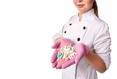 Tıbbi önlüklü, eldivenli ve elinde bir avuç dolusu tablet bulunan kimliği belirsiz kadın doktor ya da hemşirenin görüntüsü...