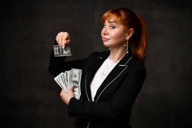 Mücevherci kadın, beyaz bluz ve siyah ceket. Gülümseyen ve gri arka planda duran yüz dolarlık banknotların hayranını gösteren