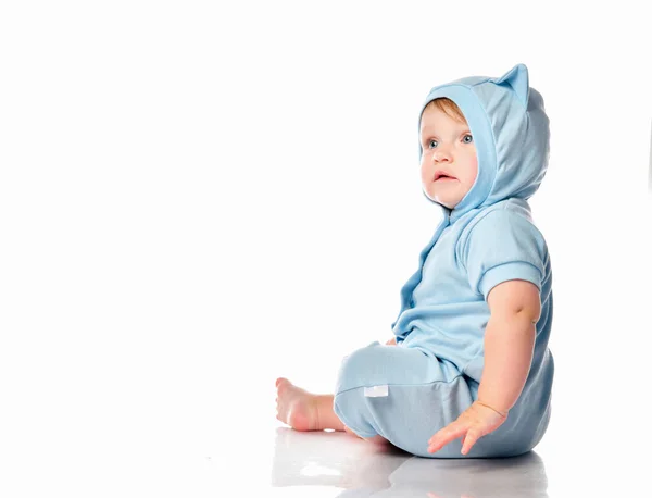 웃는 파란 양복을 입은 아기가 바닥에 앉아 혀를 내보이는 모습 — 스톡 사진