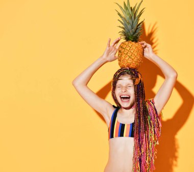 Kafasında ananas tutan neşeli, at kuyruklu bir kız..