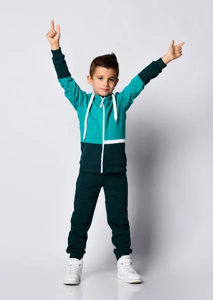 Chłopiec w dresie, adidasy stoją z podniesionymi ramionami — Zdjęcie stockowe