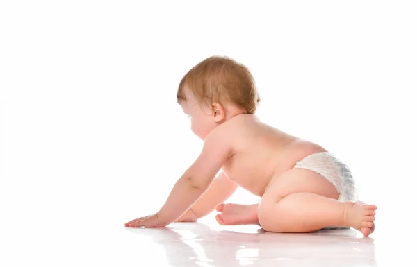 Rampant petit garçon nu en couches dans le studio sur un fond blanc. Un garçon pieds nus aux yeux bleus est sur le point de ramper vers l'avant. — Photo