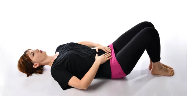 Atletik bayan antrenör kendi üzerinde nefes egzersizleri gösteriyor..