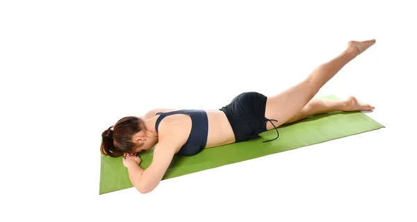 Woman lies face down on a sports mat and does an exercise to stretch her legs. — Stock Photo, Image