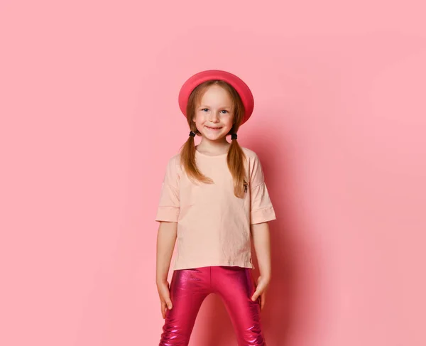 Menina bonito elegante em um chapéu rosa e leggings posando em um fundo vermelho. — Fotografia de Stock