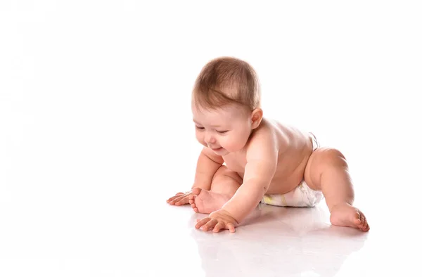 Pequeno bebê brincando no chão sobre fundo branco — Fotografia de Stock