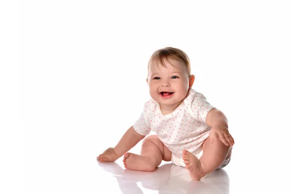 Happy laughing baby girl sitting on studio floor — Stock Photo, Image