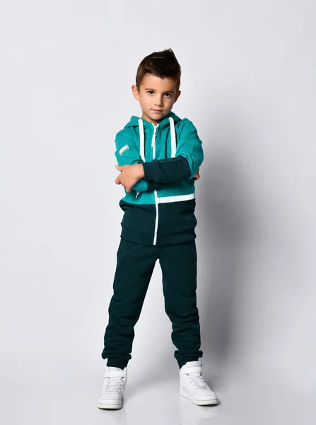 Renkli eşofmanlı, gri arka planda spor ayakkabılı esmer bir çocuk.. — Stok fotoğraf