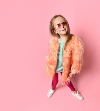 şık giyinen ve kameraya poz veren gözlüklü bir kız. Tam uzunlukta çekim pembe üzerinde izole edildi, kopyala boşluk