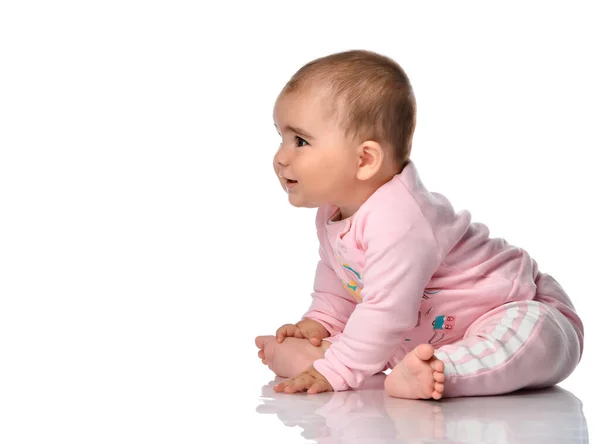 Child sits sideways looks away and smiles on a white background. — Stock Photo, Image