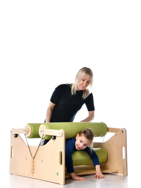 Little girl and her mother showing principles of training on compact exercise equipment for children with special needs, isolated on white, copy space — Stock Image Little girl and her mother showing principles of training on compact exercise equipment for children with special needs, isolated on white, copy space Stock Photo