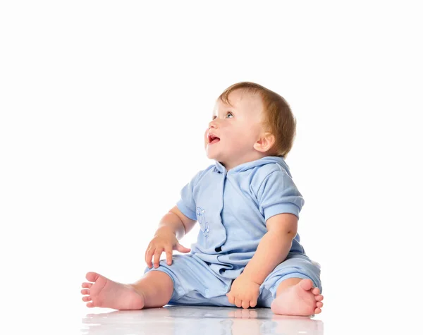 Baby in blue jumpsuit sitting on floor looking up — Stock Photo, Image