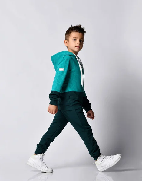 Boy in tracksuit, sneakers walking isolated on grey — Stock Photo, Image