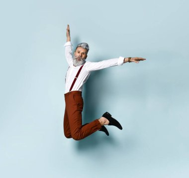 Mavi arka planda atlayan şık gri saçlı kazaklı şık bir adam. Gençlik ve yaşlılık kavramı.