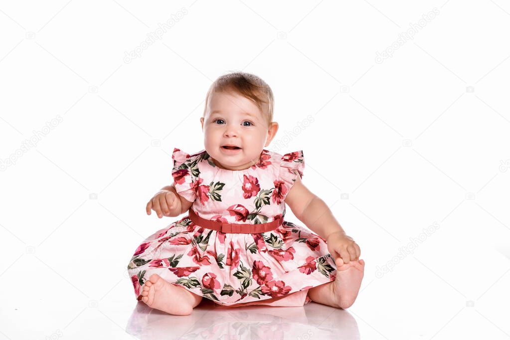Pretty baby in beautiful dress sitting on floor