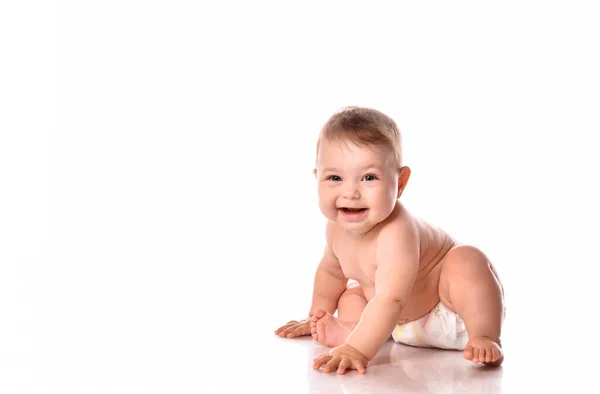 Söt småbarn i blöjor ler glatt på vit bakgrund — Stockfoto