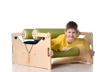 Gülümseyen küçük çocuk, egzersiz seti düzensizliğini gösteriyor. Beyazlara izole edilmiş, kopyalama alanı.