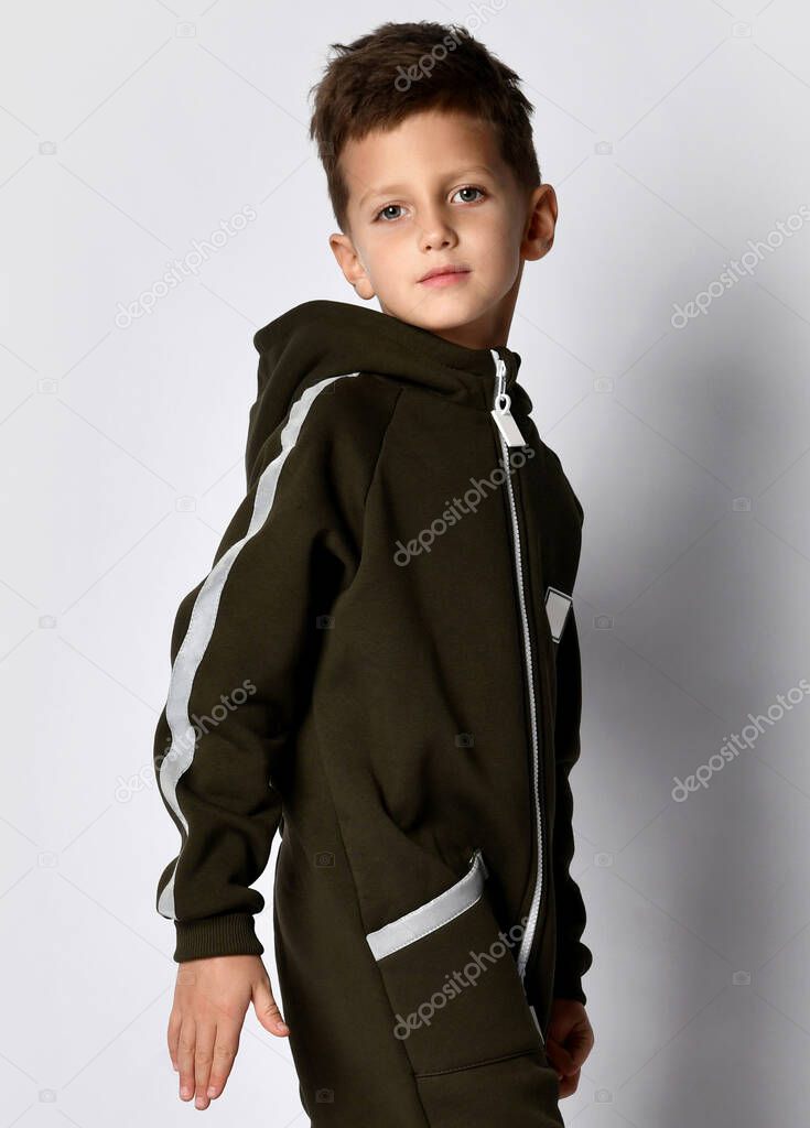 boy advertises a fashionable sports model for children posing for the camera in a warm overalls against the background of a studio wall.