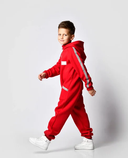 Мальчик, идущий в красном теплом комбинезоне — стоковое фото