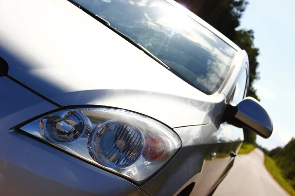 Zonnig weer, grijze auto op de achtergrond weg. Dorp stijl, zomer. Mirroring van de hemel op de auto. — Stockfoto