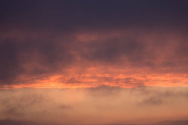 Kılçık bulutlara. Ateşli kırmızı yükselen Güneş bulutların arkasında. Bunun başlık