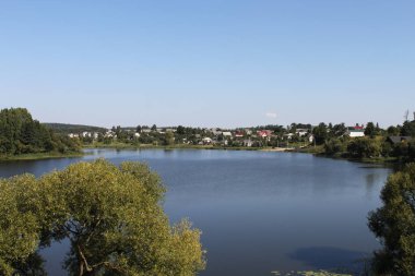 ağaçlar ile kıyıdan göl manzarası. Güneşli bir gün, mavi gökyüzü. Kırsal