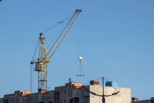 Planta de construcción con grúa amarilla sobre fondo azul cielo. Construcción, trabajos de construcción, levantamiento de cargas pesadas —  Fotos de Stock