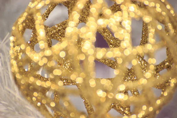 Braided blur shiny gold ball hangs on a white spruce. Decorations for the Christmas tree. Iridescent light in the reflection of the ball. new year mood. screensaver, background for postcards