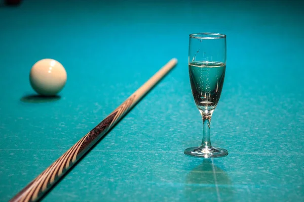 a glass of champagne is on the pool table. the winner of the game, the champion drinks a glass of sparkling wine. Hobbies, sports, passionate people.