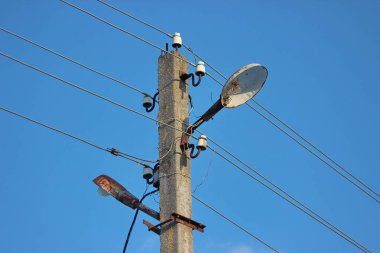 aydınlatma direği ile ışık ve teller. Elektrik mavi güneşli gökyüzü karşı tel için birçok bağlantıları ile beton direk.