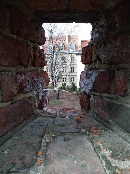 look through the red brick wall at the modern buildings. historic centre. a mysterious landscape peeking out of the hole. A loophole in the wall. protecting the city from attacks