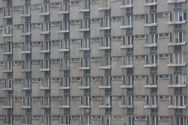 Fenster eines Mehrfamilienhauses, symmetrische Rahmen in einem grauen Haus. viele Zimmer in einem Haus. moderner Wohnungsbau. — Stockfoto