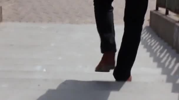 Un uomo scende le scale in una giornata di sole. un uomo che indossa pantaloni neri e scarpe nere, passo veloce . — Video Stock