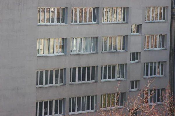 Weiße Kunststofffenster eines Mehrfamilienhauses, symmetrische Rahmen in einem grauen Haus. viele Zimmer in einem Haus. moderner Wohnungsbau. Altbau — Stockfoto