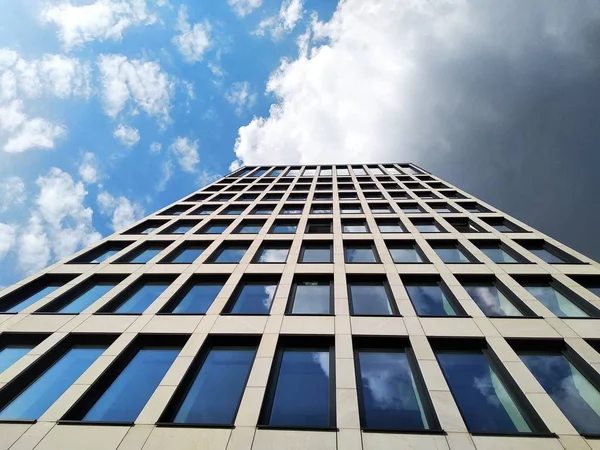 Bâtiment moderne, vue du bas. immeuble de bureaux à étages, gratte-ciel. verre et béton est une tendance de la construction moderne. lits de fleurs dans la ville de pierre. prendre soin de l'environnement — Photo