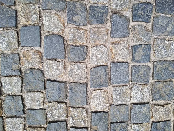 The road surface of the stones - paving stones. the road, made for many years, reliable road surface in old cities. age-old buildings. texture and color of natural stones. — Stock Photo, Image