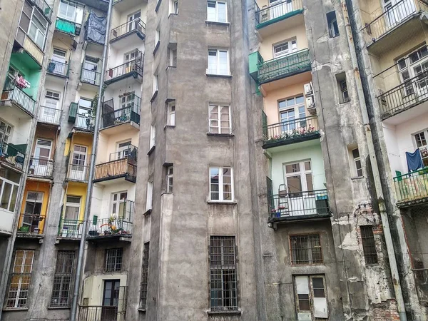 old gray Soviet house, crumbling walls, on the balconies of people\'s things, warehouse. the color of the terraces is different on all floors