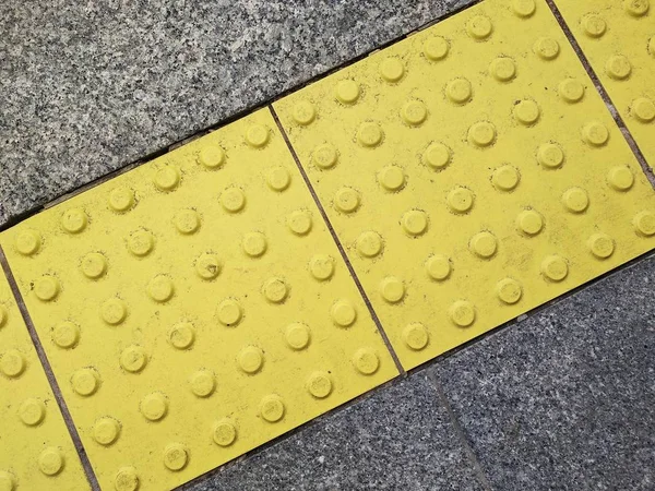 Traffic safety for people with visual impairment. special equipment for the free movement of persons with disabilities. bright yellow tiles with tactile elements. — Stock Photo, Image